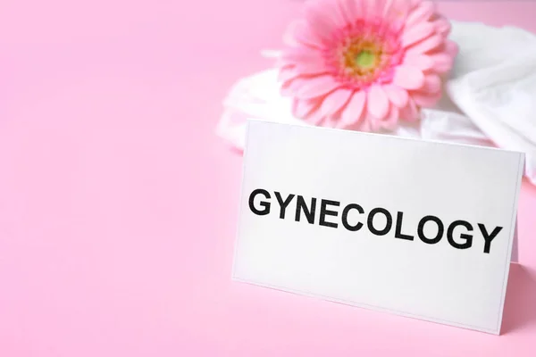 Carte avec mot gynécologie, serviettes menstruelles emballées et fleur sur fond de couleur. Espace pour le texte — Photo