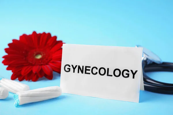 Carte avec mot Gynécologie, stéthoscope, tampons et fleur sur fond de couleur — Photo