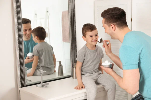 Vater sprüht Sohn im Badezimmer Rasierschaum ins Gesicht — Stockfoto