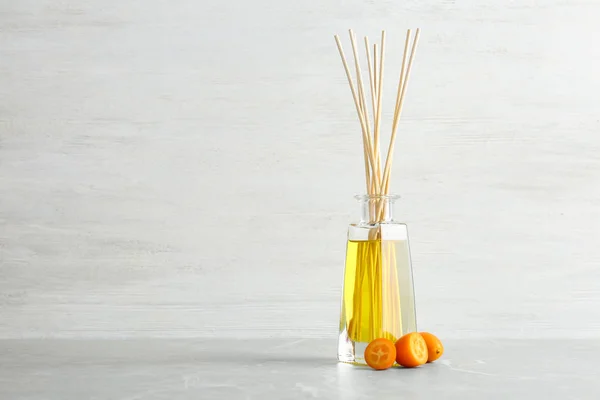 Reed freshener aromático e kumquat na mesa contra fundo claro. Espaço para texto — Fotografia de Stock