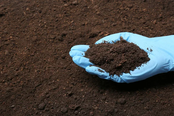 Wetenschapper Holding stapel grond boven de grond, close-up. Ruimte voor tekst — Stockfoto