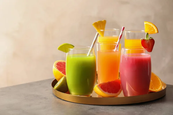 Tray with glasses of different juices and fresh fruits on table. Space for text — Stock Photo, Image