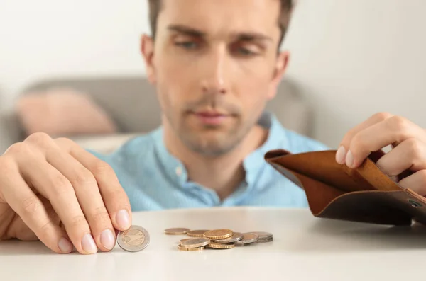 Sad man putting coins into wallet at table — Stock Photo, Image