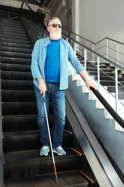 Persona ciega con bastón largo en escaleras mecánicas en interiores — Foto de Stock