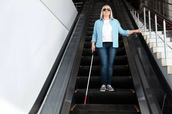 Persona ciega con bastón largo en escaleras mecánicas en interiores — Foto de Stock