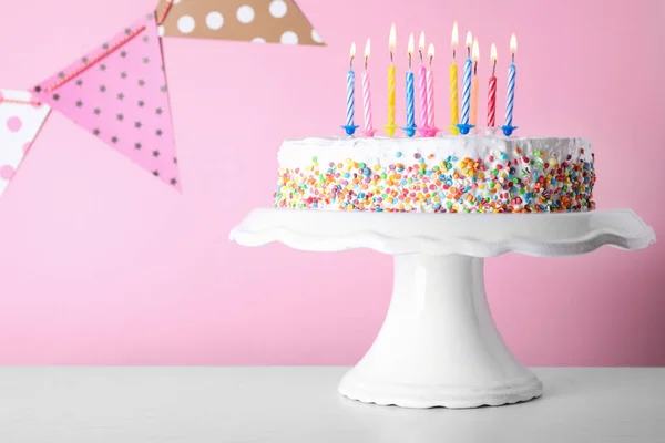 Τούρτα γενεθλίων με κάψιμο κεριών στο τραπέζι με φόντο το χρώμα. Χώρος για κείμενο — Φωτογραφία Αρχείου