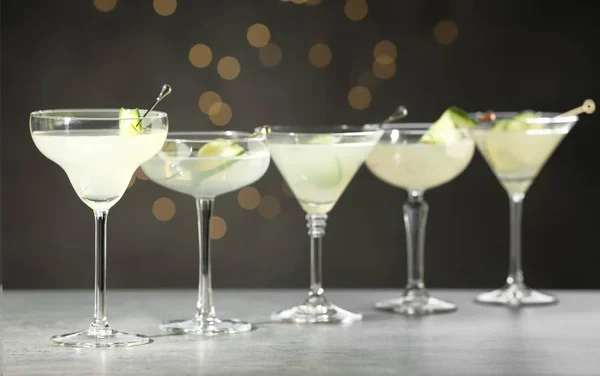 Vasos de martini con pepino sobre mesa gris contra luces borrosas — Foto de Stock