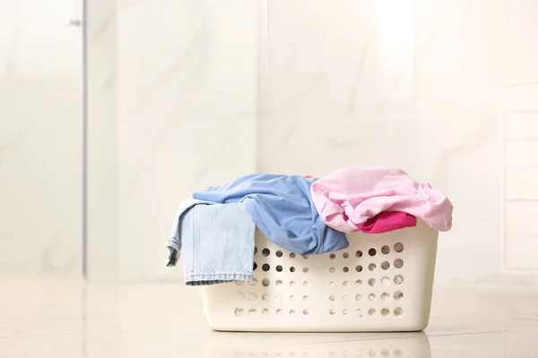 Laundry basket with dirty clothes on light background. Space for text — Stock Photo, Image