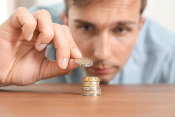 Young man stacking coins at table, focus on hand Stock Image
