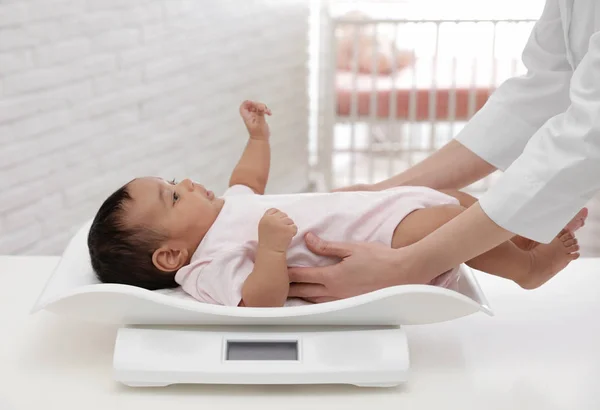Lekarz wagi African-American Baby na skale w jasnym pomieszczeniu — Zdjęcie stockowe
