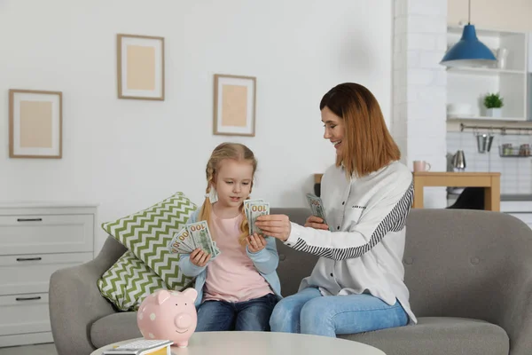 Madre e hija contando dinero en el sofá interior —  Fotos de Stock