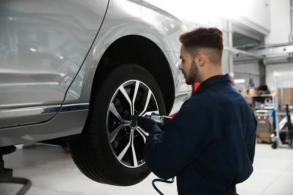 Técnico que trabalha com carro na oficina de reparação de automóveis — Fotografia de Stock