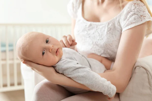 自宅でアームチェアに座っている彼女の赤ちゃんを持つ母親 — ストック写真