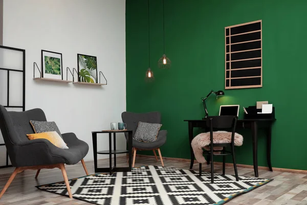 Современный интерьер гостиной с рабочим местом рядом с зеленой стеной — стоковое фото