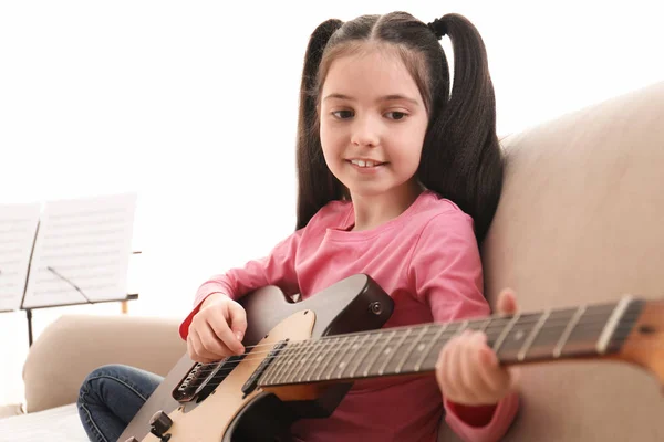 小女孩在家里弹吉他。学习音乐笔记 — 图库照片