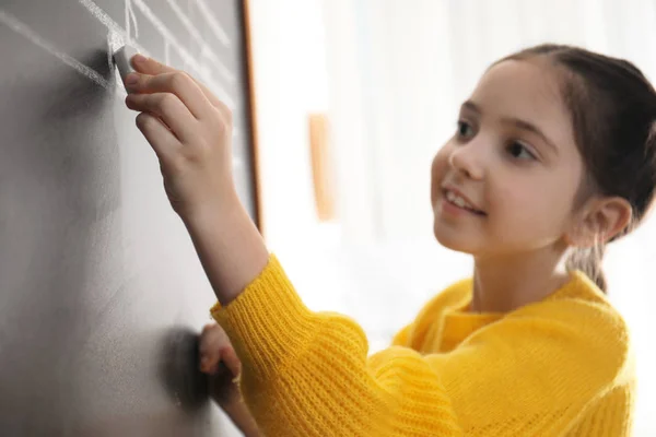 Little girl writing music notes on blackboard in classroom, closeup — Stock Photo, Image