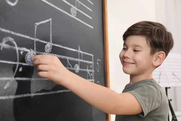 教室の黒板に音楽ノートを書く小さな男の子 — ストック写真