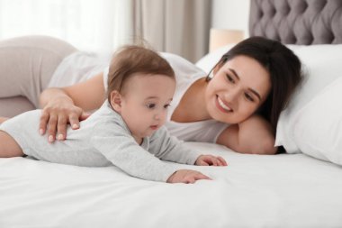 Evde yatakta yatan sevimli bebeği ile anne portresi