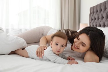 Evde yatakta yatan sevimli bebeği ile anne portresi