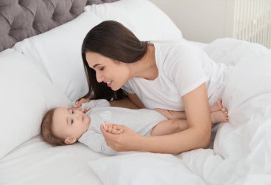 Evde yatakta yatan sevimli bebeği ile anne portresi