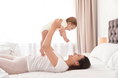 Genç Anne oyun ile onu sevimli bebek üzerinde yatak kapalı