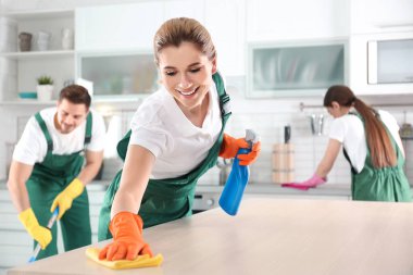 Mutfak meslektaşları ile tablo temizleme için bez ve püskürtücü kullanan kadın