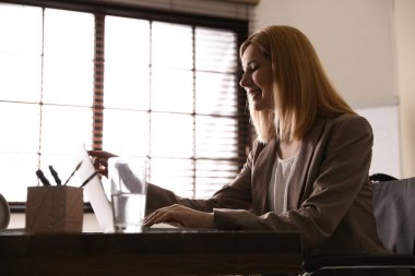 Kadın tekerlekli sandalye çalışma masasında dizüstü bilgisayar ile kapalı