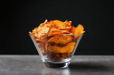 Siyah arka plan karşı masada tatlı patates cipsi ile Bowl