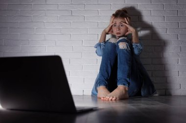 Karanlık odada dizüstü bilgisayarı olan korkmuş genç kız. İnternet tehlikesi
