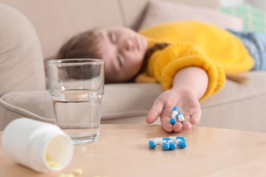 Evde kanepede hap ile bilinçsiz küçük çocuk. İlaç zehirlenmesinin tehlikesi