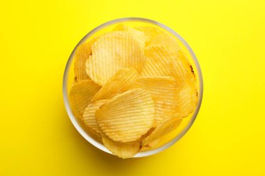 Renkli arka planda kase lezzetli gevrek patates cipsi, üst görünümü