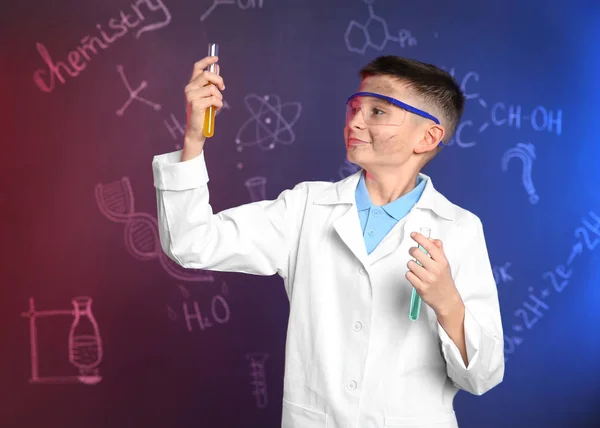 Estudante com tubos de ensaio contra quadro negro com fórmulas químicas escritas — Fotografia de Stock