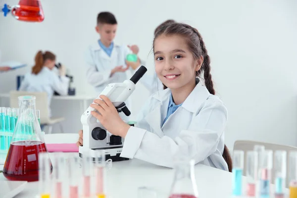 Uczennica z mikroskopem w tabeli w klasie chemii — Zdjęcie stockowe