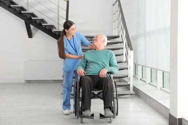 Νοσοκόμα βοηθώντας ανώτερος άνθρωπος σε αναπηρικό αμαξίδιο στο νοσοκομείο — Φωτογραφία Αρχείου