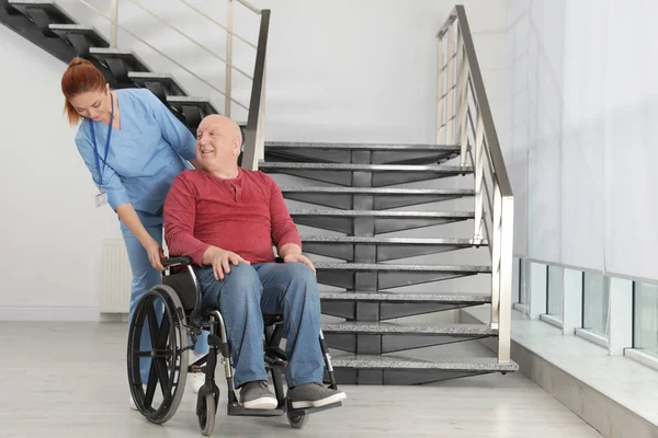 Pielęgniarka pomagające starszy mężczyzna na wózku inwalidzkim w szpitalu — Zdjęcie stockowe