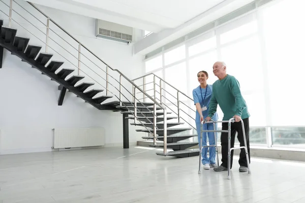 Enfermera asistiendo a hombre mayor con andador en el hospital — Foto de Stock