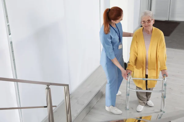 Sjuk sköterska bistå Senior kvinna med Walker på sjukhus — Stockfoto