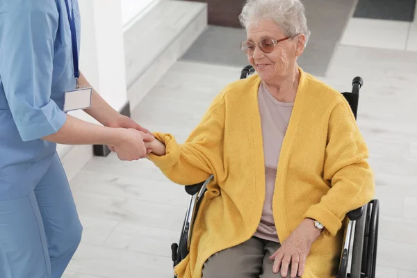 Νοσοκόμα βοηθώντας ανώτερη γυναίκα σε αναπηρικό αμαξίδιο στο νοσοκομείο — Φωτογραφία Αρχείου