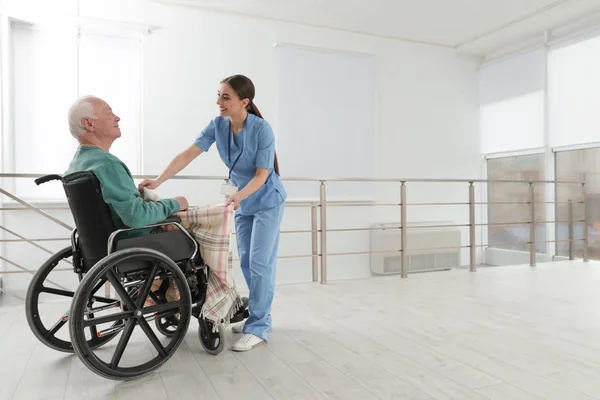 Verpleegkundige voor senior man in rolstoel met Plaid in het ziekenhuis. Medische hulp — Stockfoto