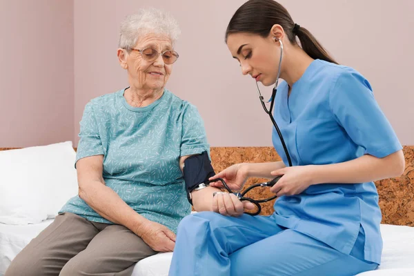 Verpleegkundige het meten van senior vrouw de bloeddruk in het ziekenhuis Ward. Medische hulp — Stockfoto