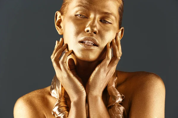 Porträt einer schönen Dame mit Goldfarbe auf der Haut vor grauem Hintergrund, Nahaufnahme — Stockfoto