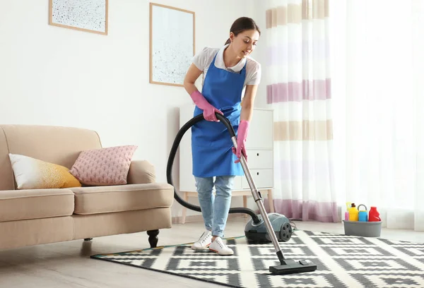 Mulher hoovering tapete na sala de estar. Serviço de limpeza — Fotografia de Stock