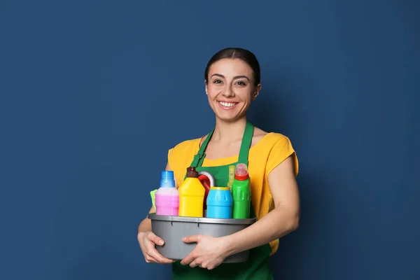 Woman with basin of detergents on color background — 스톡 사진