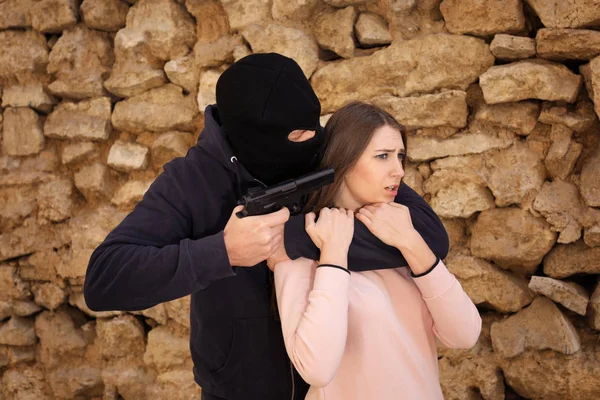 Μασκοφόρος άνθρωπος με όπλο που κρατά όμηρο μια γυναίκα σε εξωτερικούς χώρους. Ποινικό αδίκημα — Φωτογραφία Αρχείου