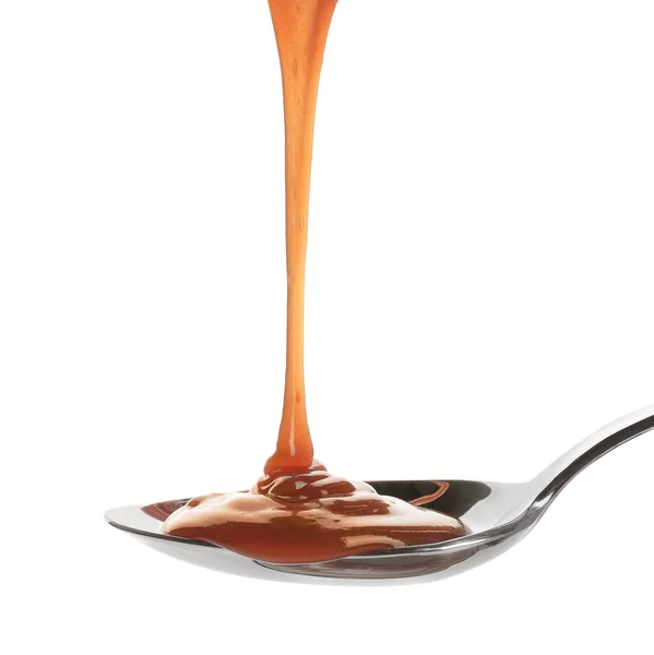 Savoureux caramel sauce verser dans une cuillère isolée sur blanc — Photo