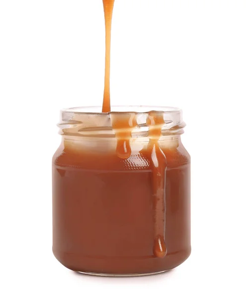 Sabrosa salsa de caramelo vertiendo en frasco aislado en blanco — Foto de Stock