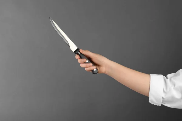 Woman holding carving knife on grey background, closeup. Space for text