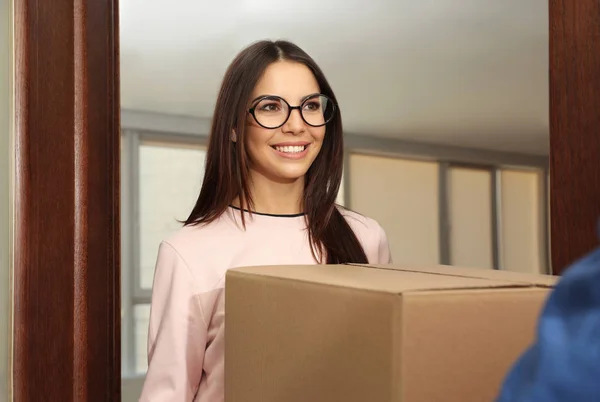 Kvinna tar emot paket från leverans service courier inomhus — Stockfoto