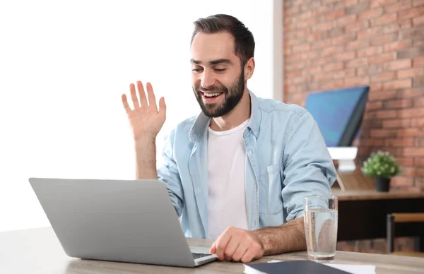Hombre joven usando chat de vídeo en el ordenador portátil en la oficina en casa —  Fotos de Stock