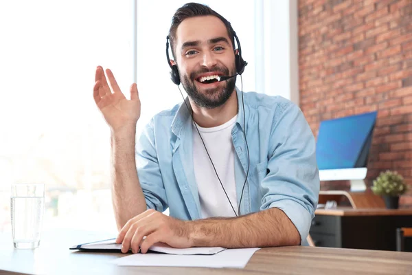 Jongeman met headset op zoek naar camera en met behulp van video chat in het thuiskantoor — Stockfoto